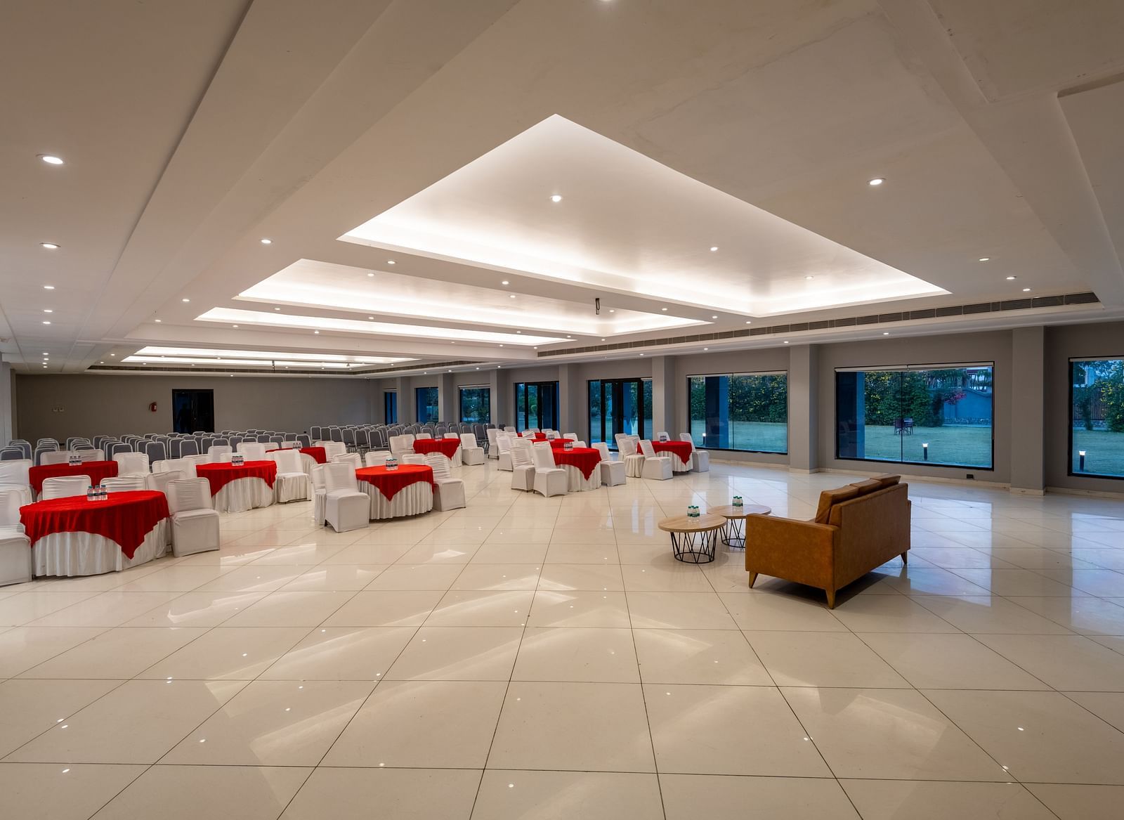 Side view of tables with neatly decorated tablecloths, a plush sofa, and two round tables set in front at DLS Forest Vines Resort.